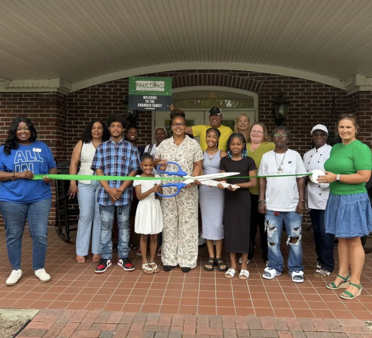 Sanaya Solenai cutting the ribbon at the Paulding Chamber of Commerce, surrounded by family and community members